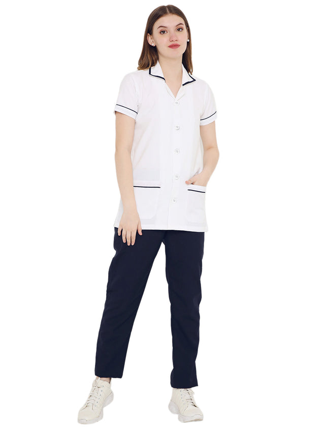 Women's white assistant apron and navy pant set in premium polycotton, featuring pockets and contrast piping.