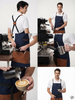 Barista wearing the Raymond Navy denim CrossBack apron with leather strap while making coffee at a bar