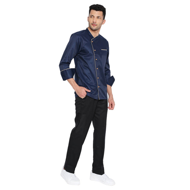 Navy blue full sleeve chef coat with cream piping, French cuffs, and buttons, worn by a model paired with black pants.